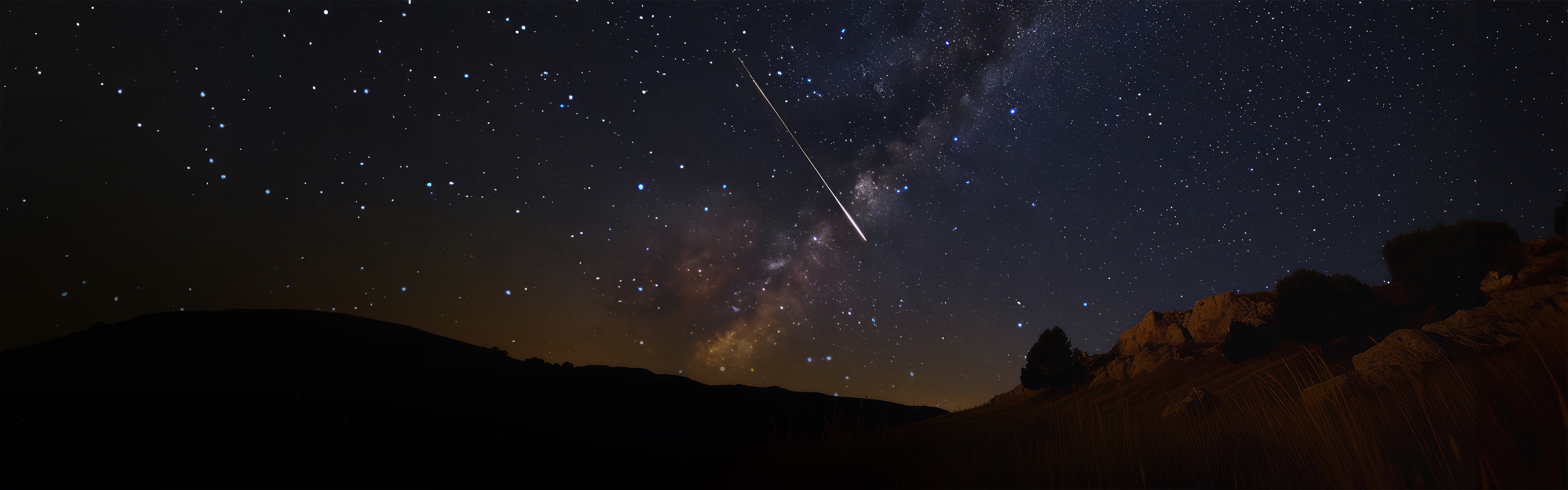Ciel nocturne étoilé avec une étoile filante au-dessus d’un paysage rocheux, illustration d’une bannière promotionnelle inspirée par l’univers et la magie des astres.